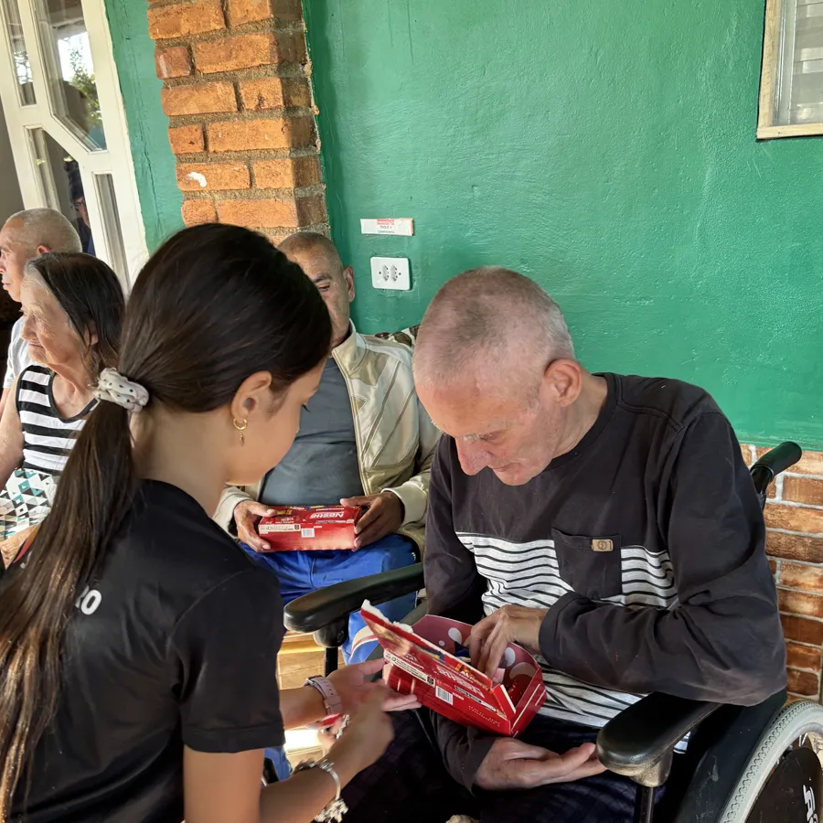 Aluna entregando caixa de bombons a um morador do lar de idosos