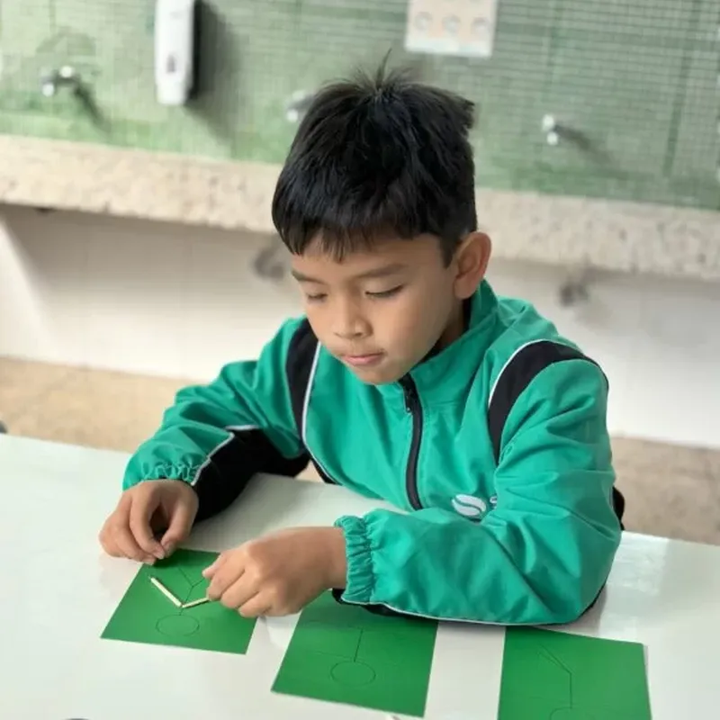 Aluno montando números com palitos em atividade de Matemática